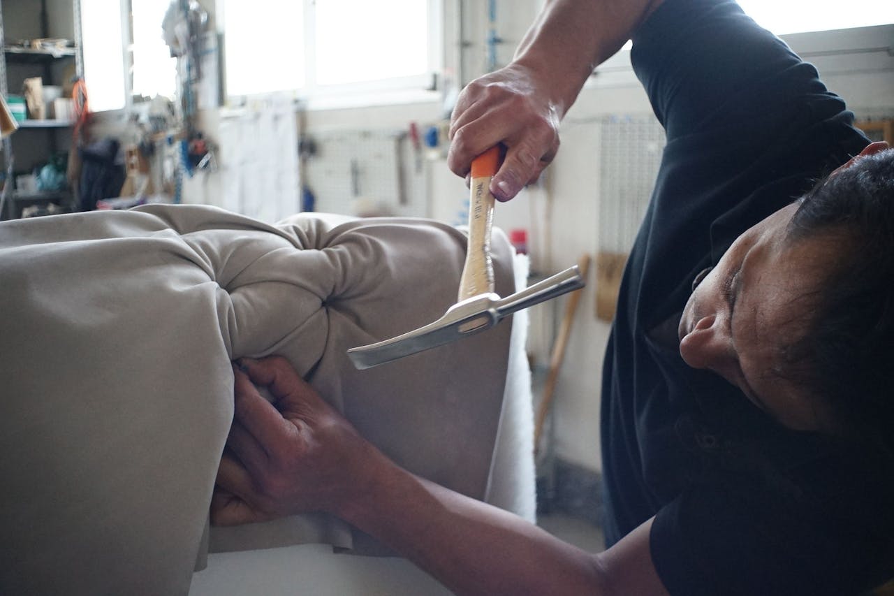 Crafting Captivating Headlines: Your awesome post title goes here Skilled artisan working meticulously on a sofa using upholstery tools in a workshop.